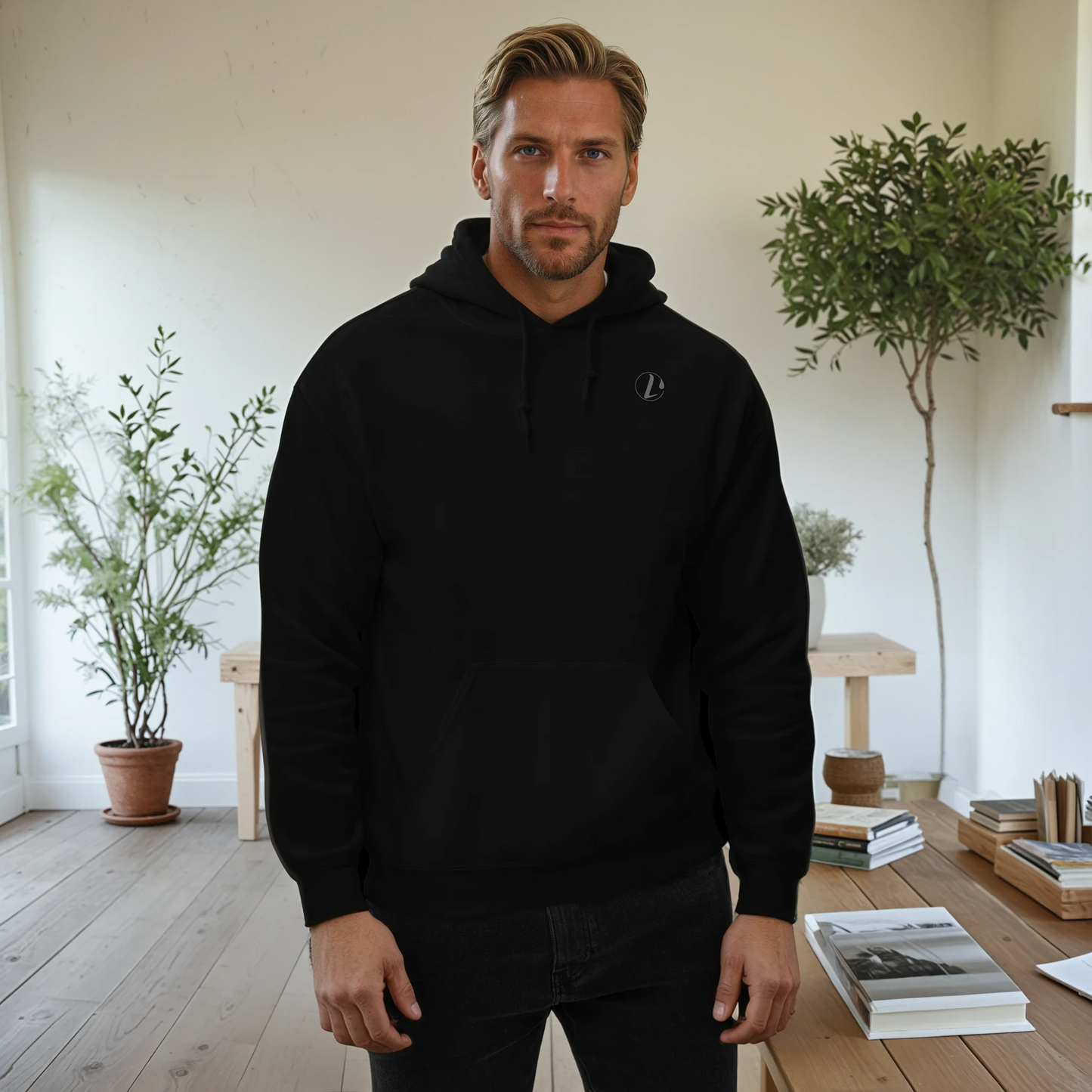 Man wearing a black hoodie in a room with plants and books.