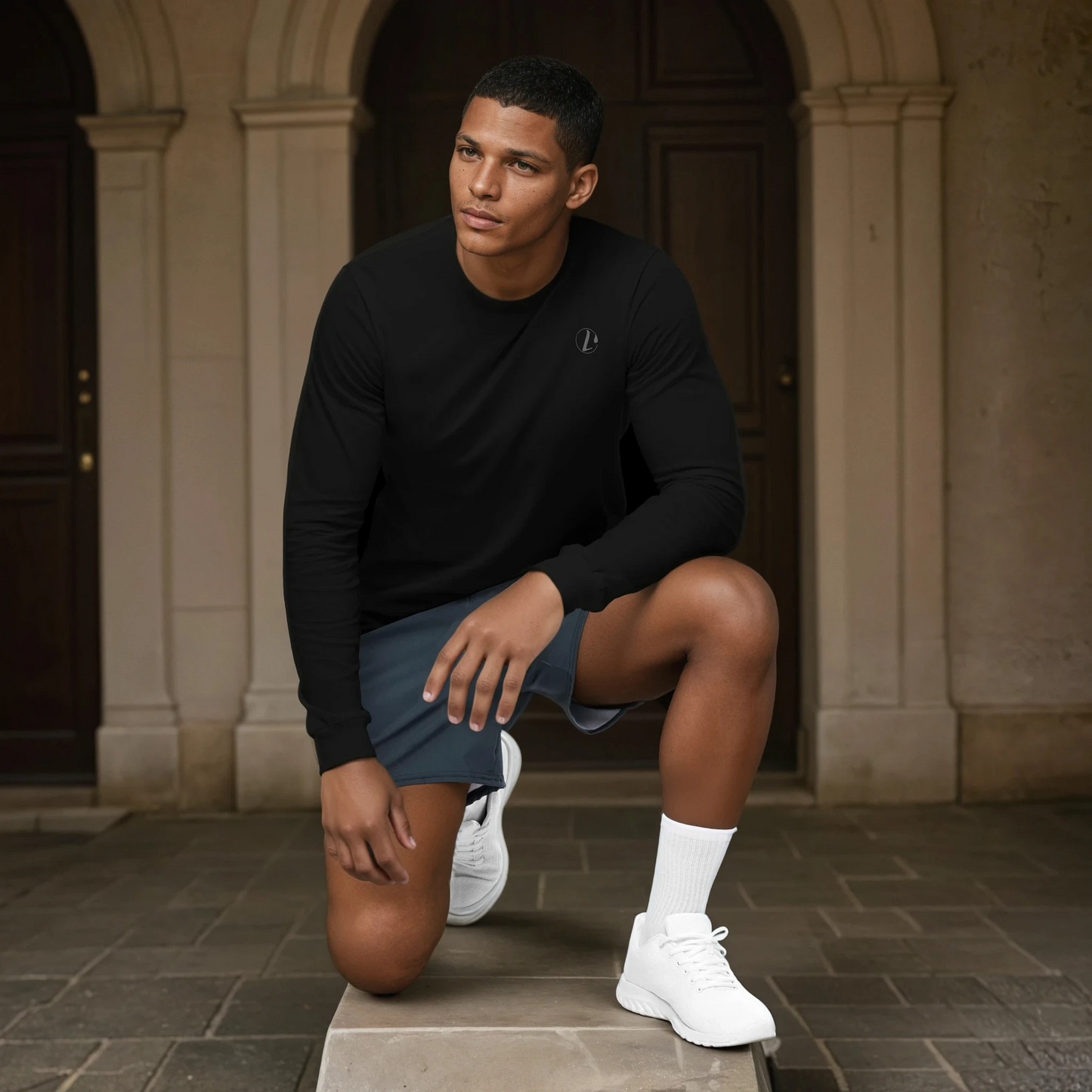 Man in black long-sleeve shirt and blue shorts posing outdoors.