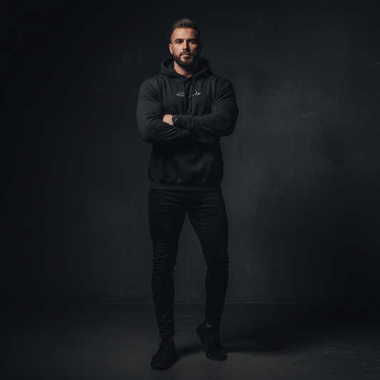 Man wearing a black hoodie and pants against a dark background