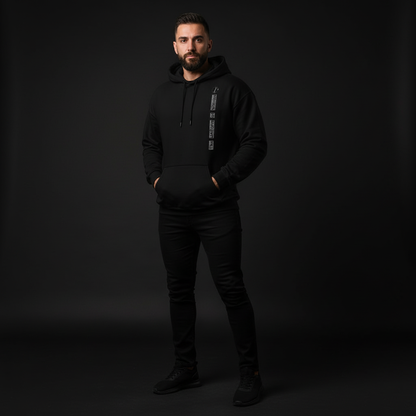 Man wearing a black hoodie and pants against a dark background, the uniform of silence