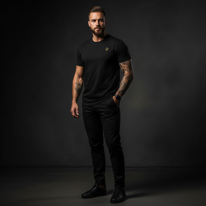 A man wearing a black t-shirt with a yellow logo against a dark background, gold logo tee