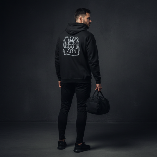 Man wearing a black hoodie with a logo on the back, born free, holding a black duffel bag against a dark background