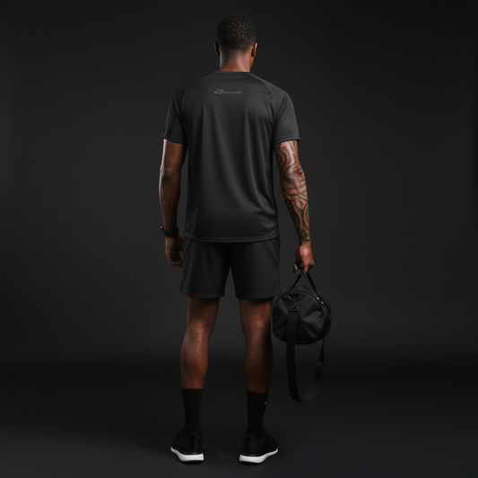 Person wearing black athletic gear holding a black duffel bag against a dark background