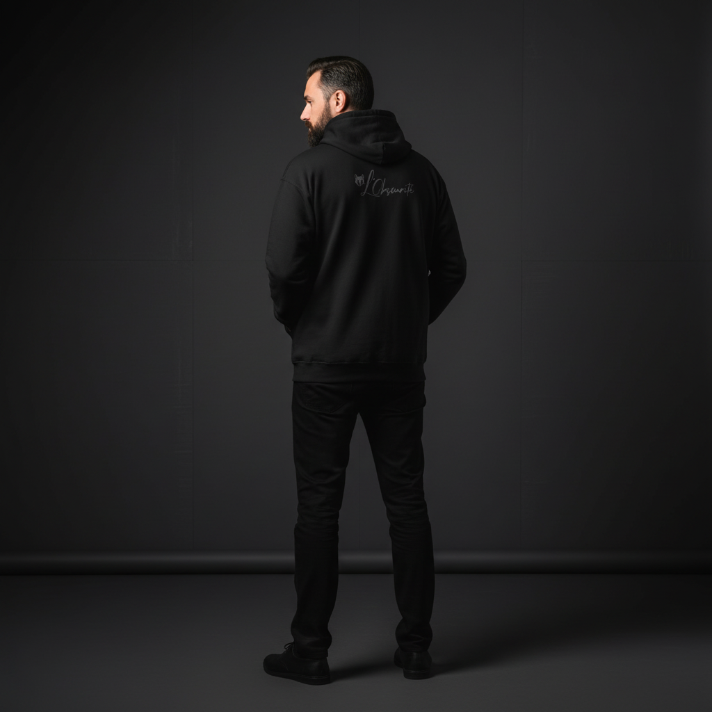 A man wearing a black zip hoodie with a logo on the back against a dark background, zip hoodie serval