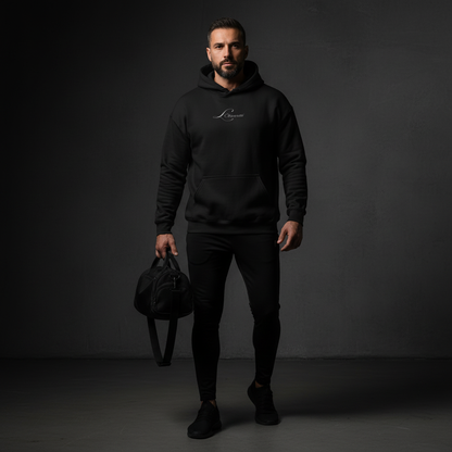 Man wearing a black hoodie with a logo, holding a black bag against a dark background, the mark hoodie